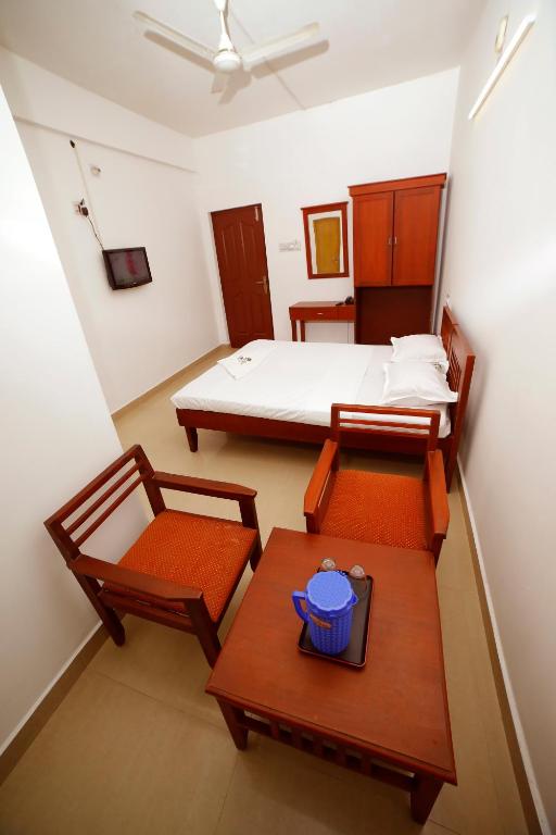 a bedroom with a bed and a table and chairs at Kairali Tourist Home in Guruvāyūr