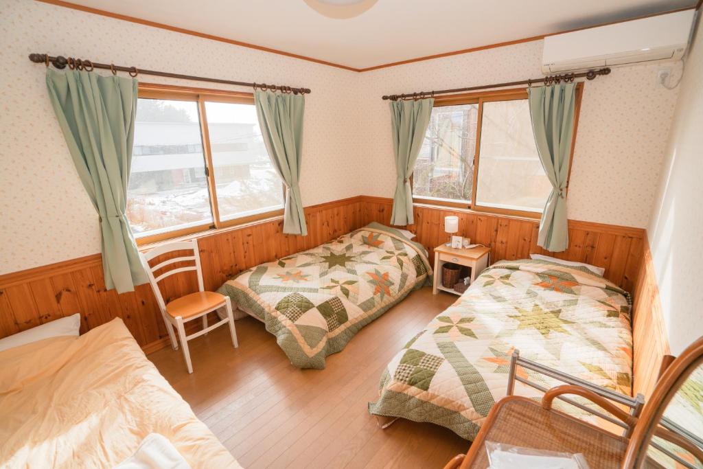 1 dormitorio con 2 camas y 2 ventanas en Guest House Chaconne Karuizawa, en Karuizawa