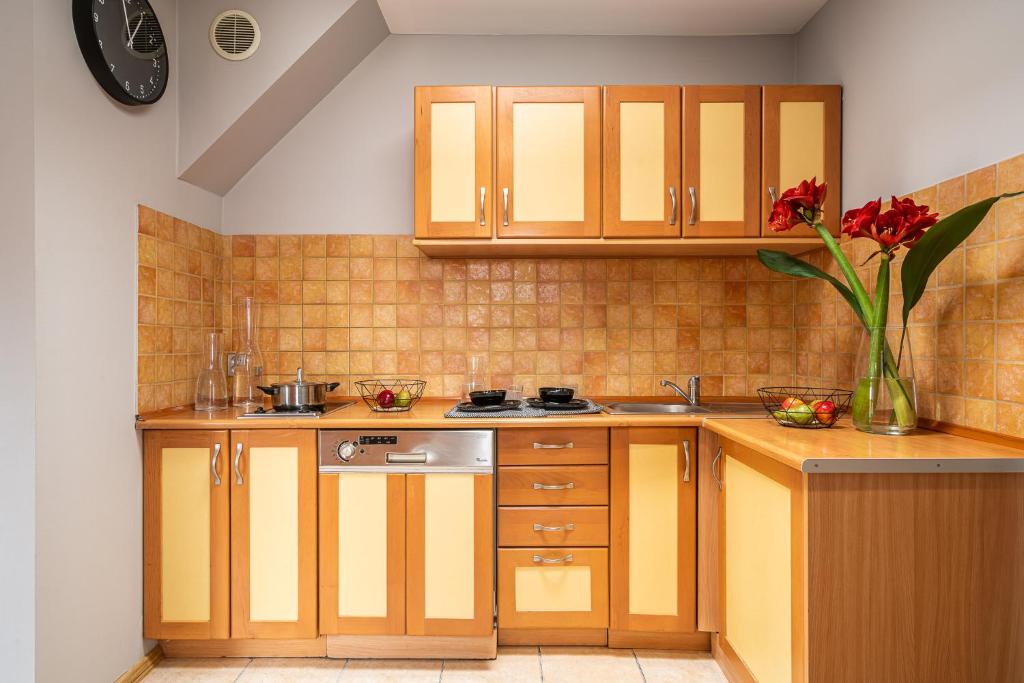 a kitchen with wooden cabinets and a vase with red flowers at Absynt Hostel Wrocław in Wrocław