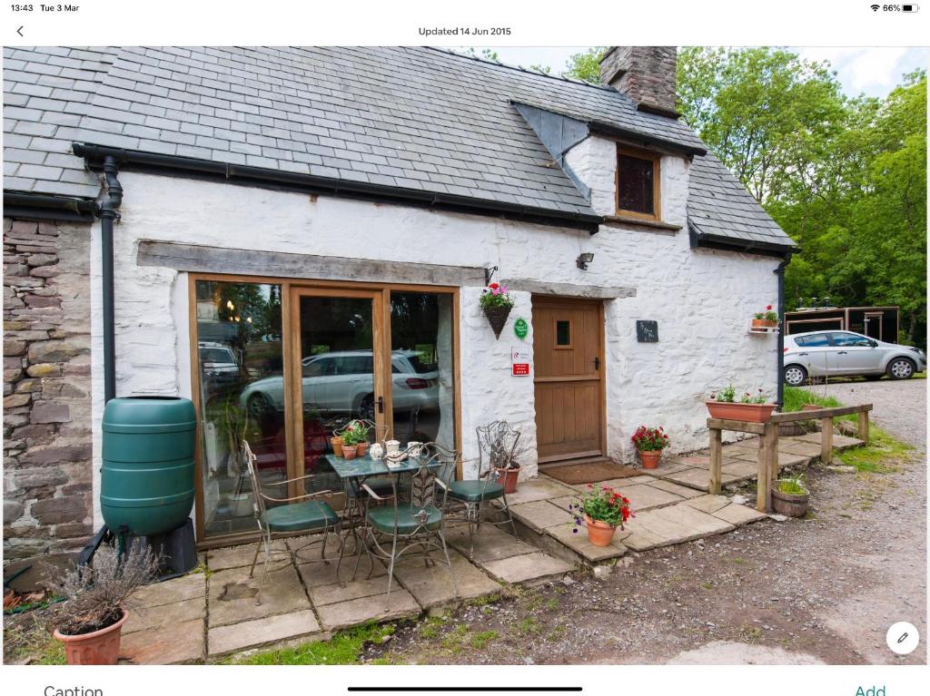 a house with a table and chairs in front of it at Ty Fferm Hen, Ancient Farmhouse, Coity Bach in Talybont