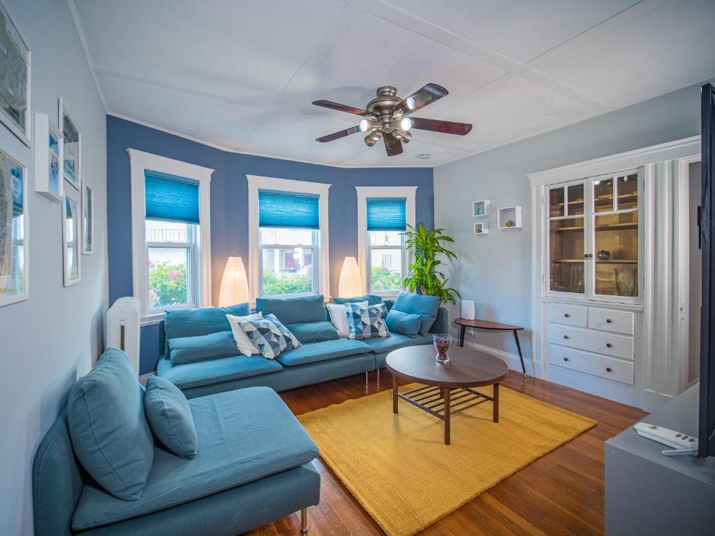 uma sala de estar com sofás azuis e uma ventoinha de tecto em 25 Ellis Av em Medford