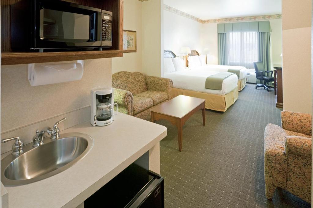 a hotel room with a sink and a bedroom at Holiday Inn Express Hotel & Suites Eagle Pass by IHG in Eagle Pass