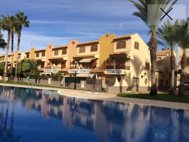 un gran edificio con palmeras y una piscina en SDB Alojamientos, en Puerto de Mazarrón