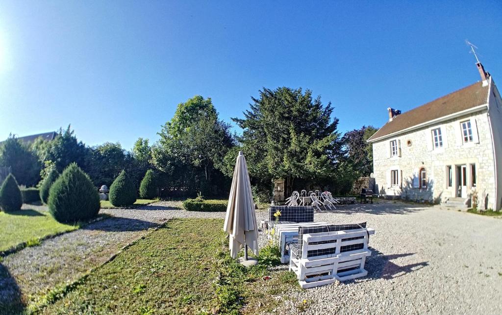 una sombrilla y una silla frente a una casa en Gîte Jura Lac Emeraude, en Clairvaux-les-Lacs