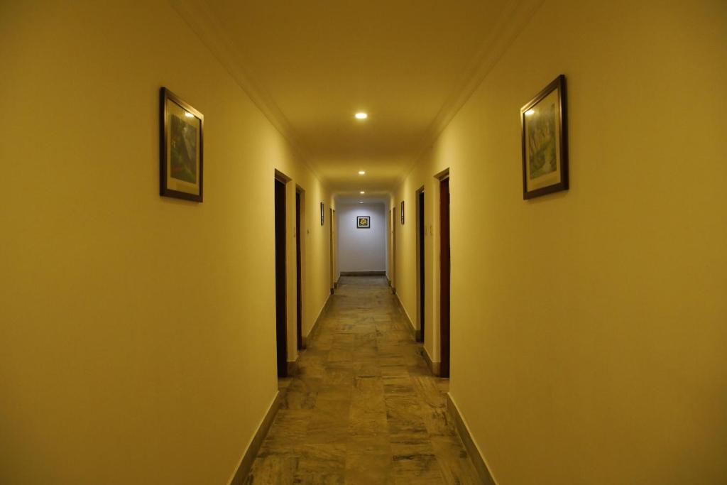 an empty hallway with yellow walls and a long corridor at Kairali Tourist Home in Guruvāyūr