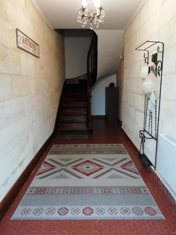 a hallway with a staircase with a tile floor and a chandelier at Logis de Villemaurine in Saint-Émilion