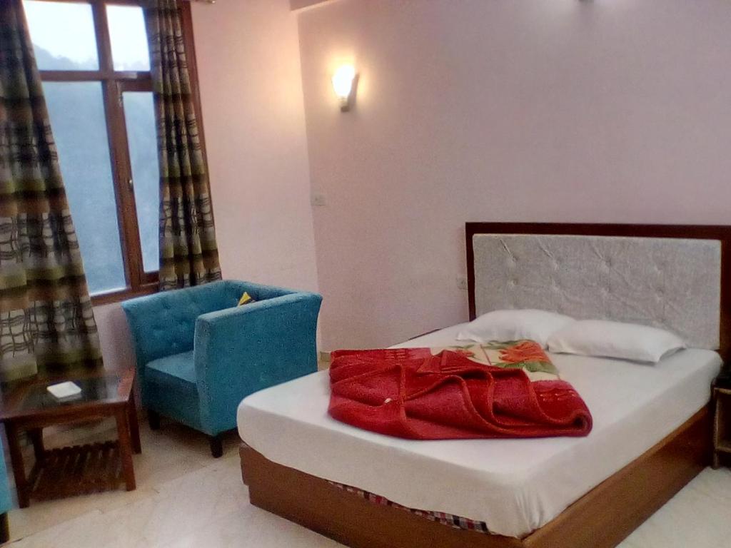 a bedroom with a bed and a blue chair and a chair at Ivy Stays in Shimla