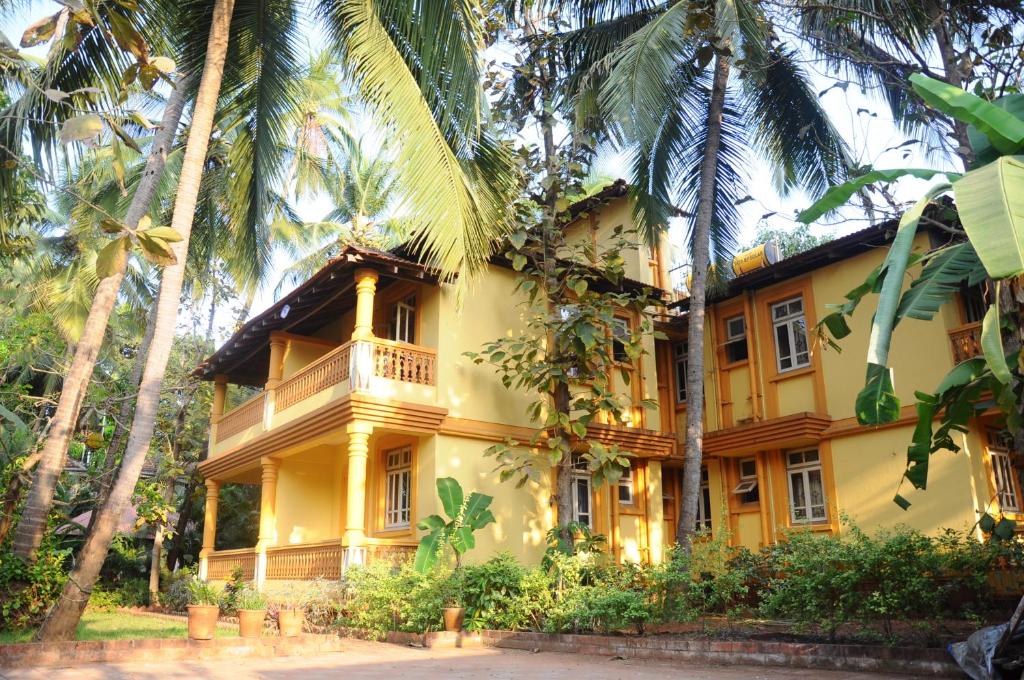 una casa gialla con palme di fronte di Palolem Guest House a Palolem