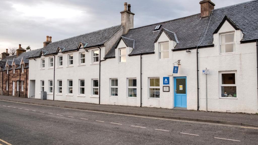 a row of white buildings on the side of a street at Ullapool Youth Hostel in Ullapool