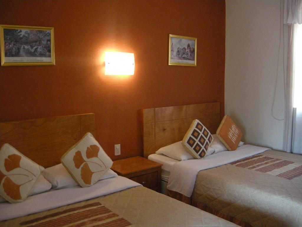 a hotel room with two beds and a window at Hotel Posada Real in Lagos de Moreno