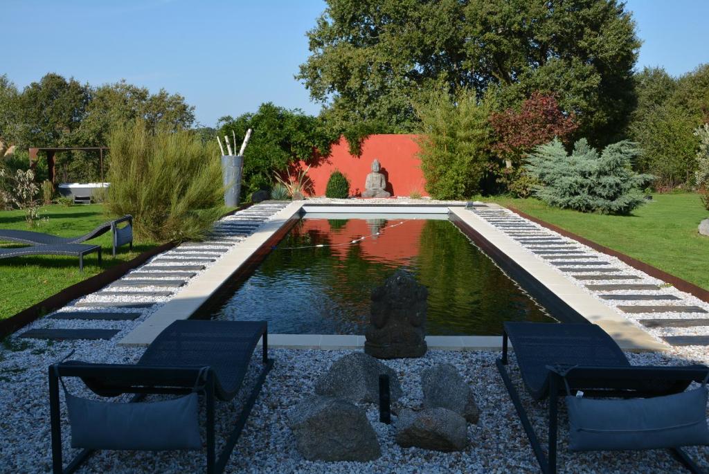 a pond in a garden with two chairs in front of it at Bébé Coin Coin in Étouars