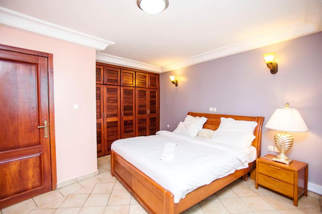a bedroom with a bed with white sheets and a lamp at Residence Le Carat in Douala