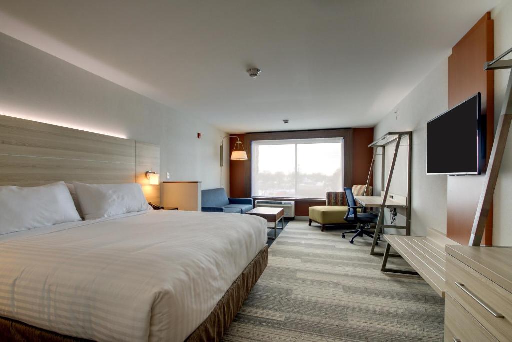 a bedroom with a bed, chair, and a window at Holiday Inn Express & Suites Galesburg, an IHG Hotel in Galesburg