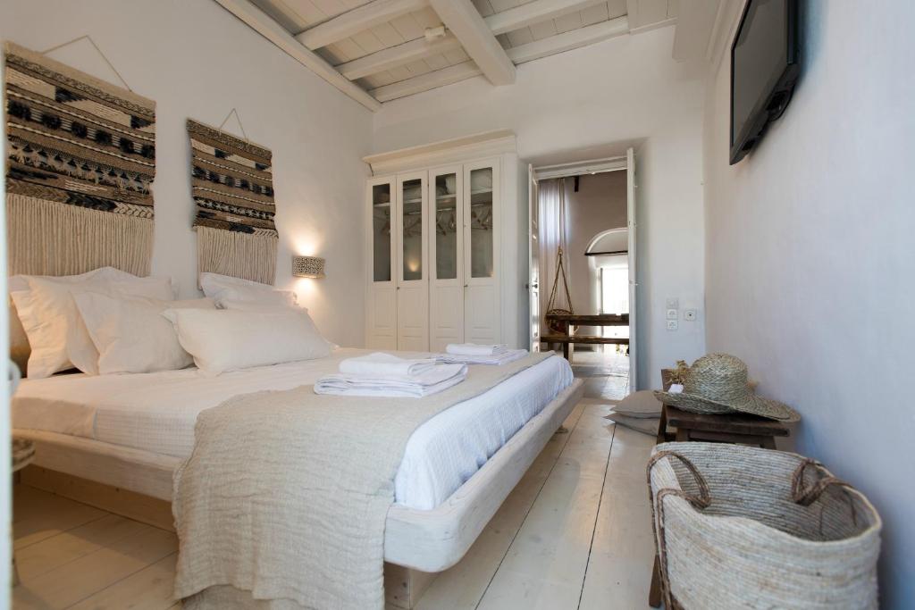a white bedroom with a bed and a television at Villa Loom Mykonos Town in Mikonos