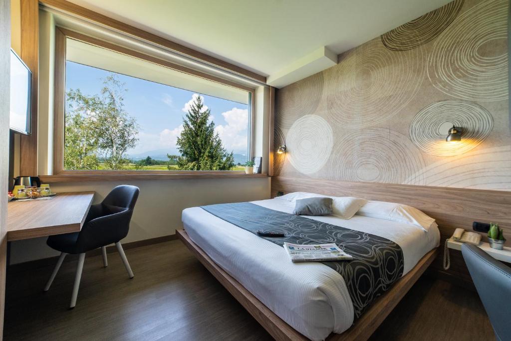 a bedroom with a bed and a desk and a window at Hotel Gardenia in Romano Canavese