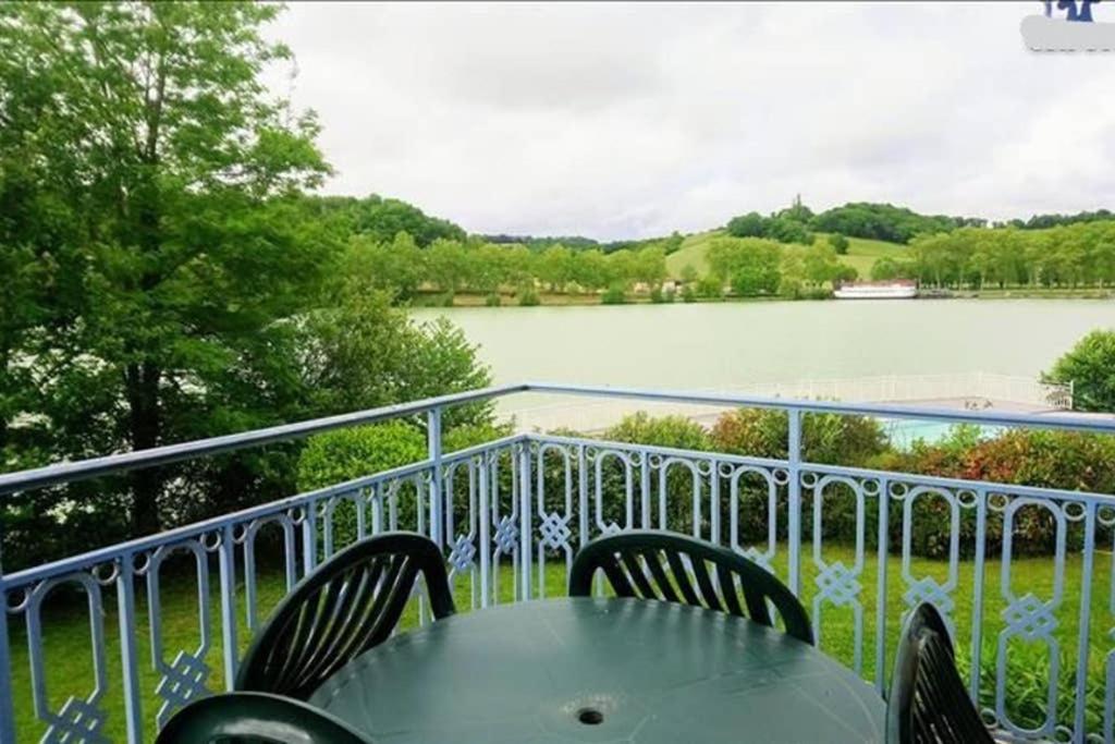 une table et des chaises sur un balcon avec vue sur un lac dans l'établissement Appt HAMEAU DU LAC (apt 142) avec piscine et vue sur le lac, à Marciac