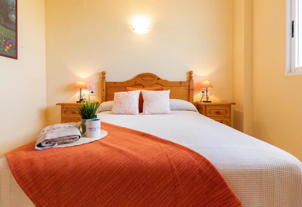 um quarto com uma cama grande e um cobertor laranja em Homes & Go Mare Internum I em La Pineda