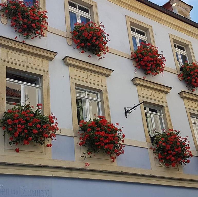 a white building with windows with red flowers on them at Ferienwohnung Ines Wolf in der Meißner Innenstadt in Meißen