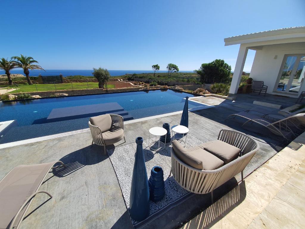 a patio with two chairs and a table next to a pool at CORALLI DEL PLEMMIRIO in Siracusa