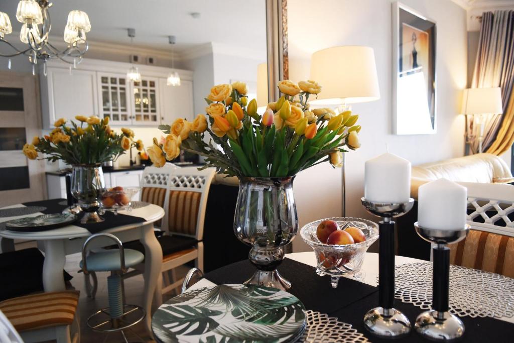a table with a vase of yellow flowers on it at Apartament Kalifornia in Międzyzdroje