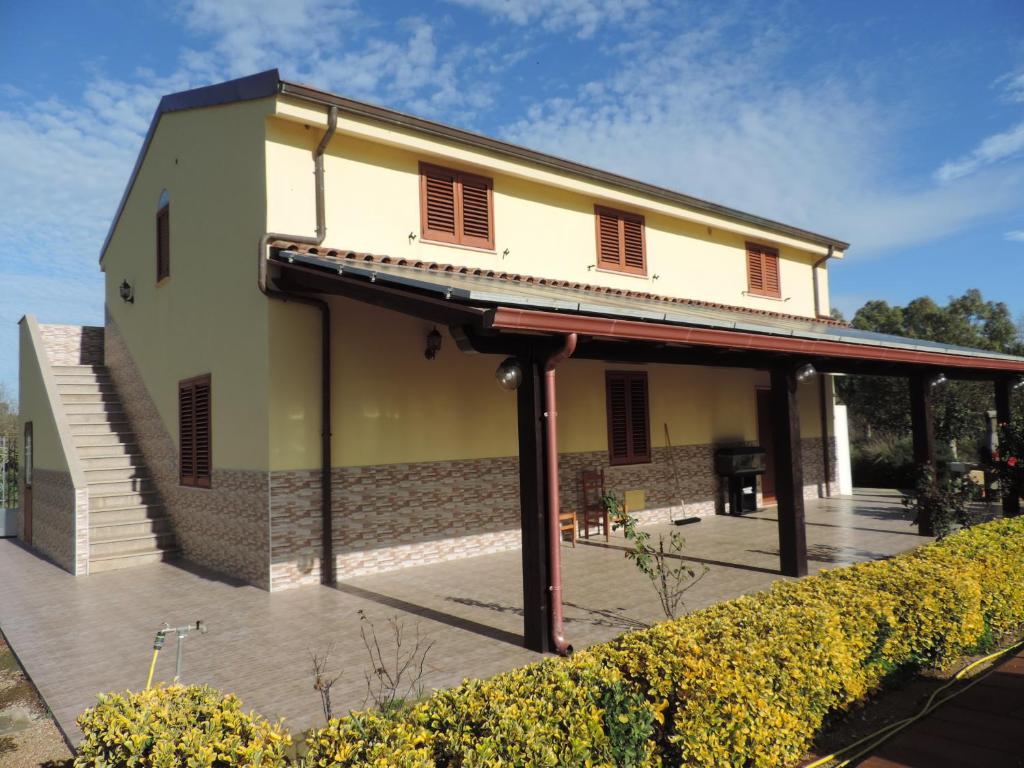 un edificio con tenda da sole accanto a un patio di Agriturismo i doni del mandorlo ad Alghero