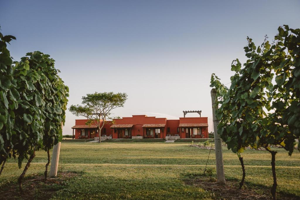 a red building in the middle of a field with trees at El Legado Wine Lodge in Carmelo