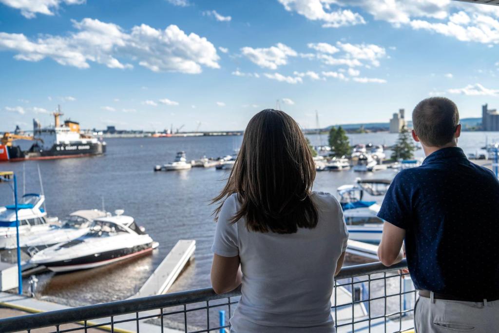 un hombre y una mujer parados en un balcón mirando barcos en Park Point Marina Inn, en Duluth