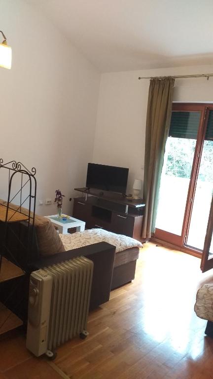 a living room with a bed and a piano at Mira apartman Oliva Residence in Petrovac na Moru