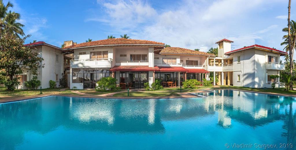 una casa grande con piscina frente a ella en Sanmali Beach Hotel, en Marawila