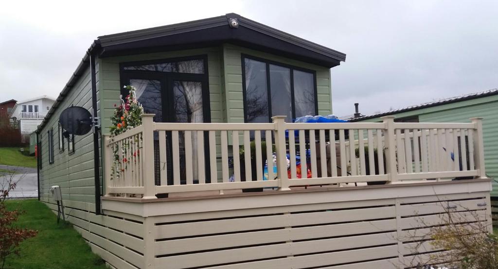 a green house with a porch and a white railing at 2 Bedrooms & Double Sofa bed Deluxe Superior Holiday Home in Gisburn