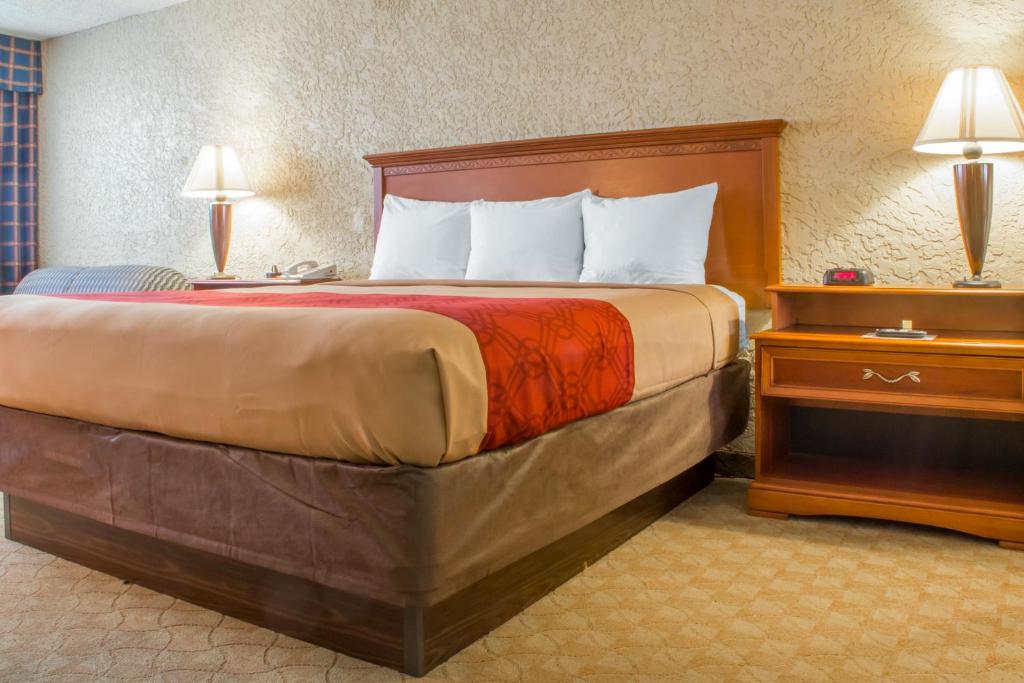 uma cama grande num quarto de hotel com duas lâmpadas em Econo Lodge Broken Arrow-Tulsa em Broken Arrow