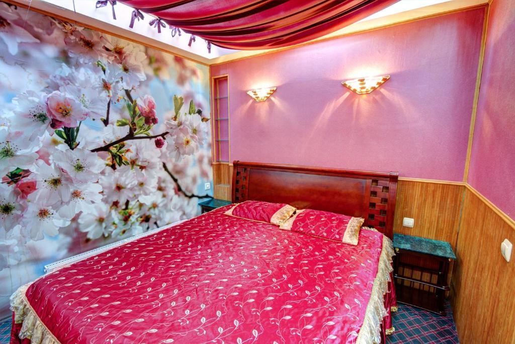 sypialnia z czerwonym łóżkiem i kwiatami na ścianie w obiekcie Маугли - дом-сказка у моря w Odessie