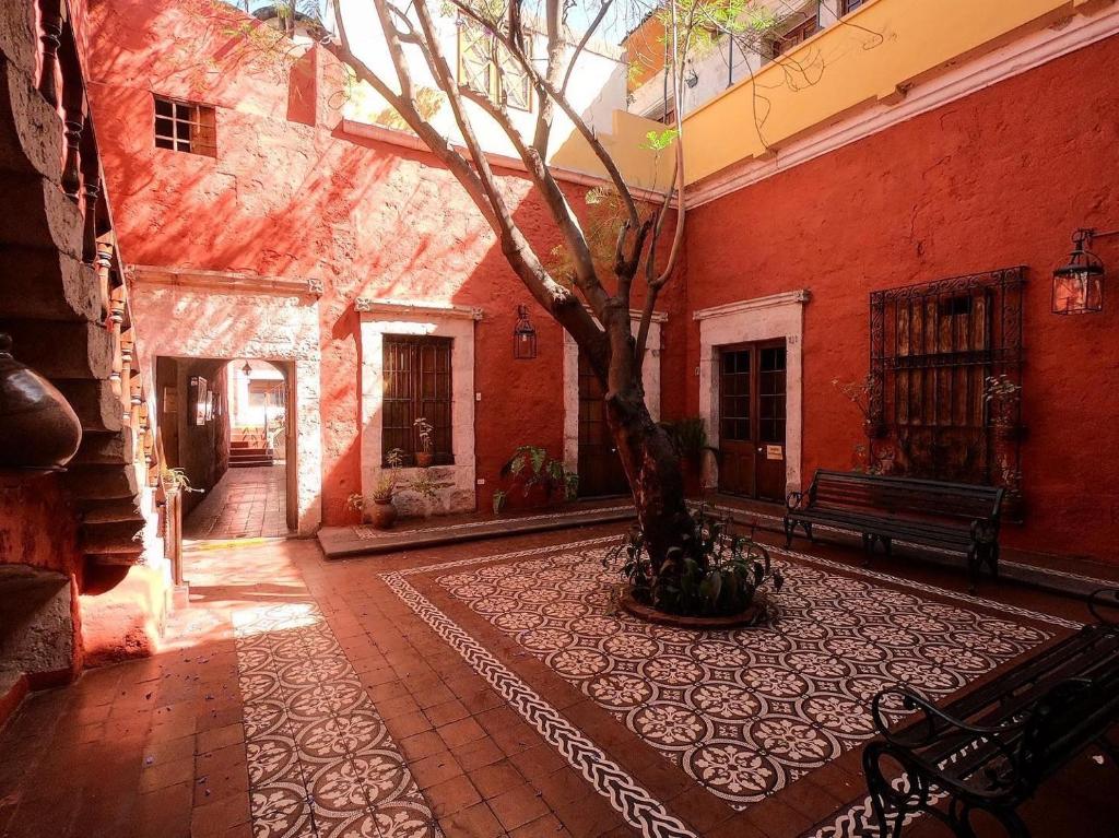 un patio con un árbol en el medio de un edificio en La Casa de Melgar, en Arequipa