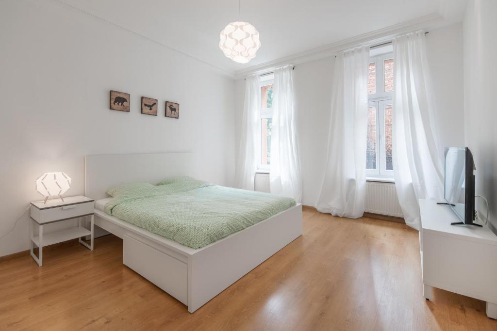 a white bedroom with a bed and a television at CITYSTAY Plac Walowy Gdansk in Gdańsk