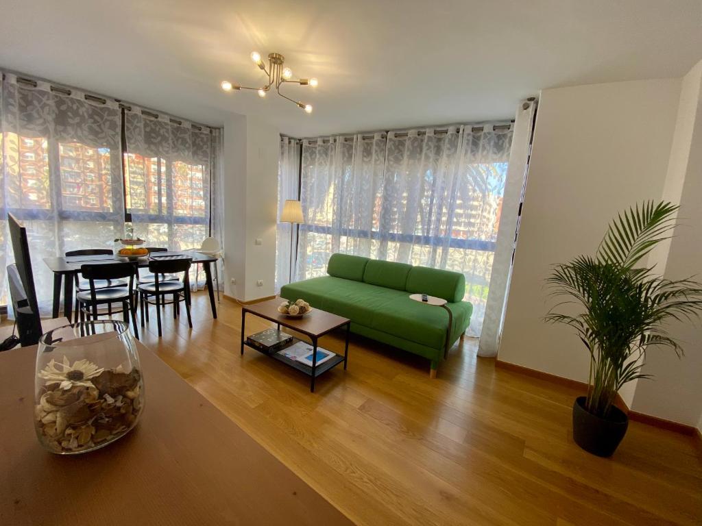 uma sala de estar com um sofá verde e uma mesa em Beach Luxury Apartment em Valência