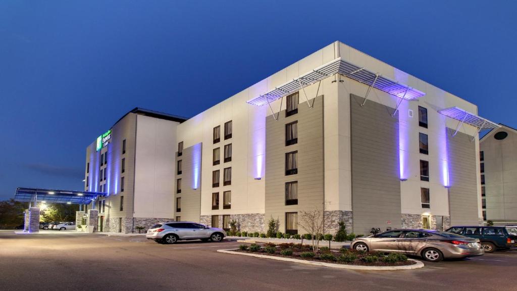 een groot gebouw met auto's geparkeerd op een parkeerplaats bij Holiday Inn Express & Suites Jackson Downtown - Coliseum, an IHG Hotel in Jackson
