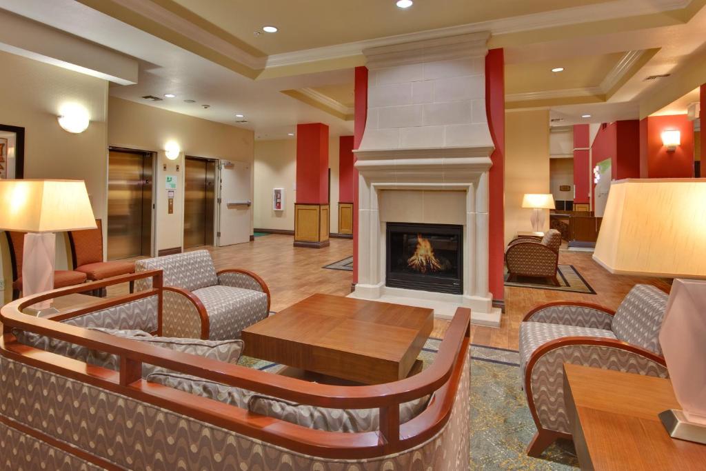 a lobby with a fireplace and a table and chairs at Holiday Inn & Suites Bakersfield, an IHG Hotel in Bakersfield