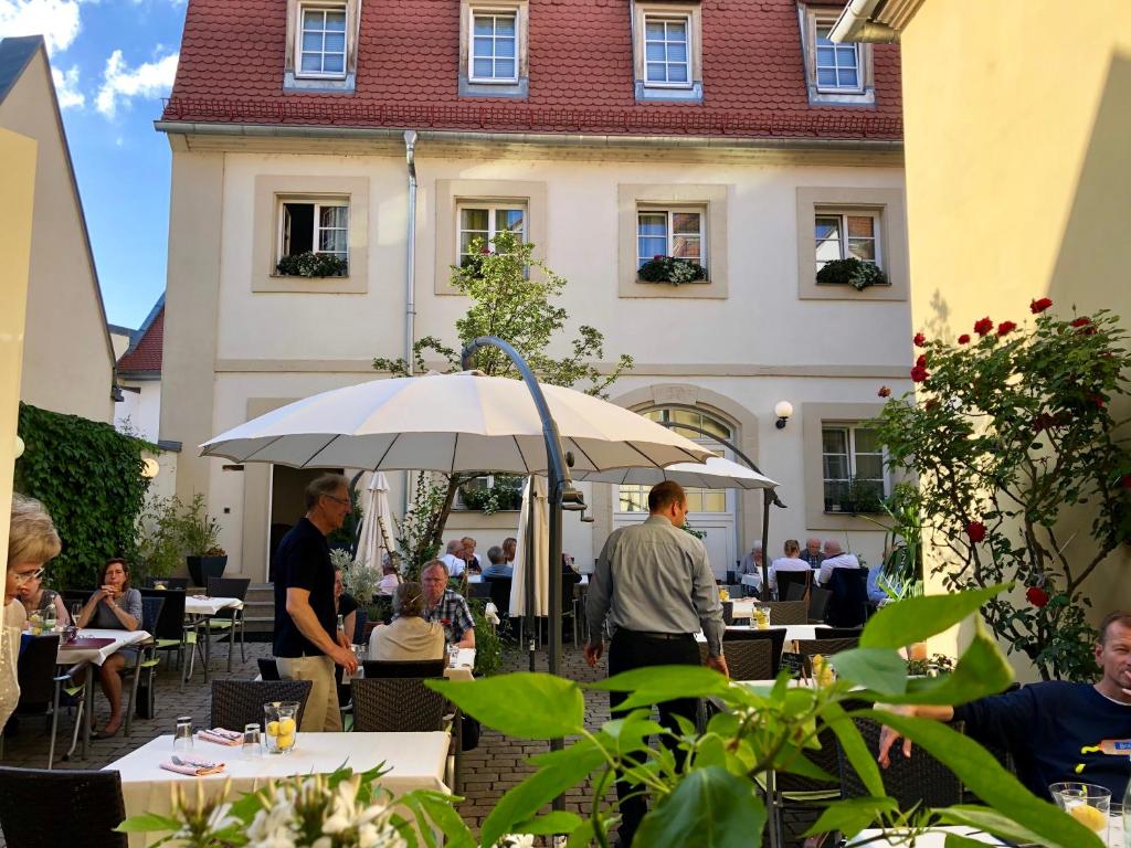 Un groupe de personnes assises à des tables avec un parapluie dans l'établissement Hotel Europa, à Bamberg
