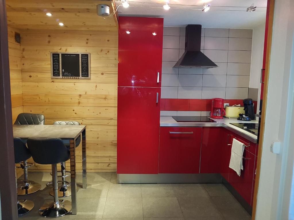 une cuisine avec des placards rouges et une table avec des chaises dans l'établissement 3 Vallées Appartement Mina, aux Menuires