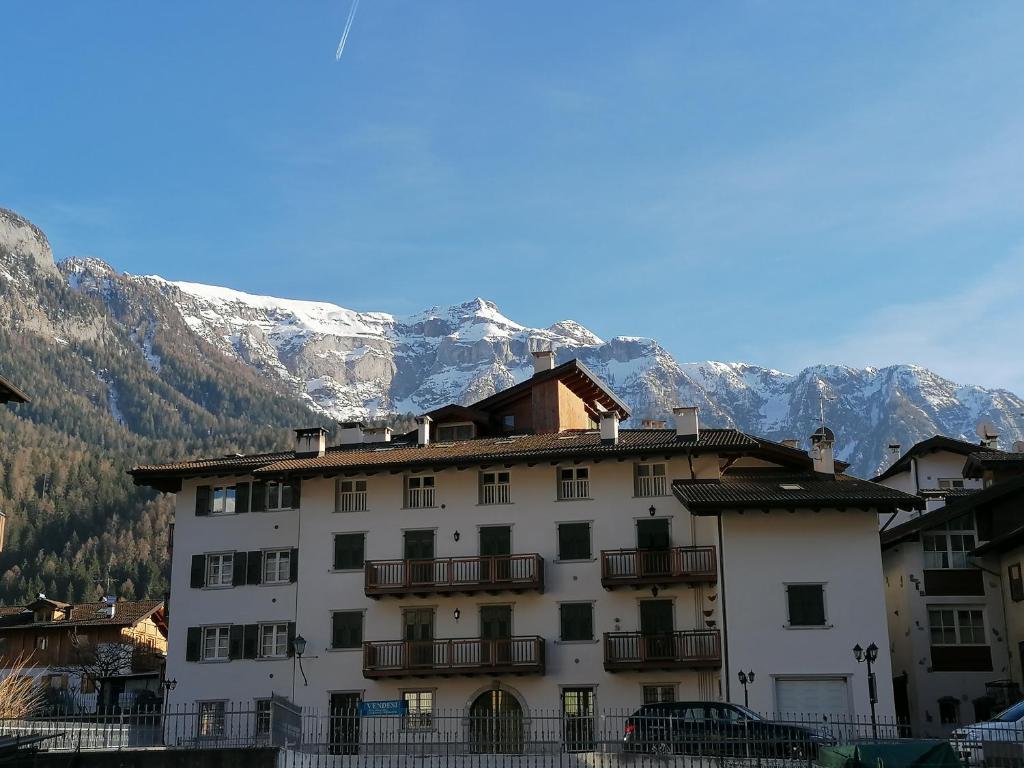 Un grand bâtiment blanc avec des montagnes enneigées en arrière-plan dans l'établissement Appartamento En Mez al Paes, à Dimaro
