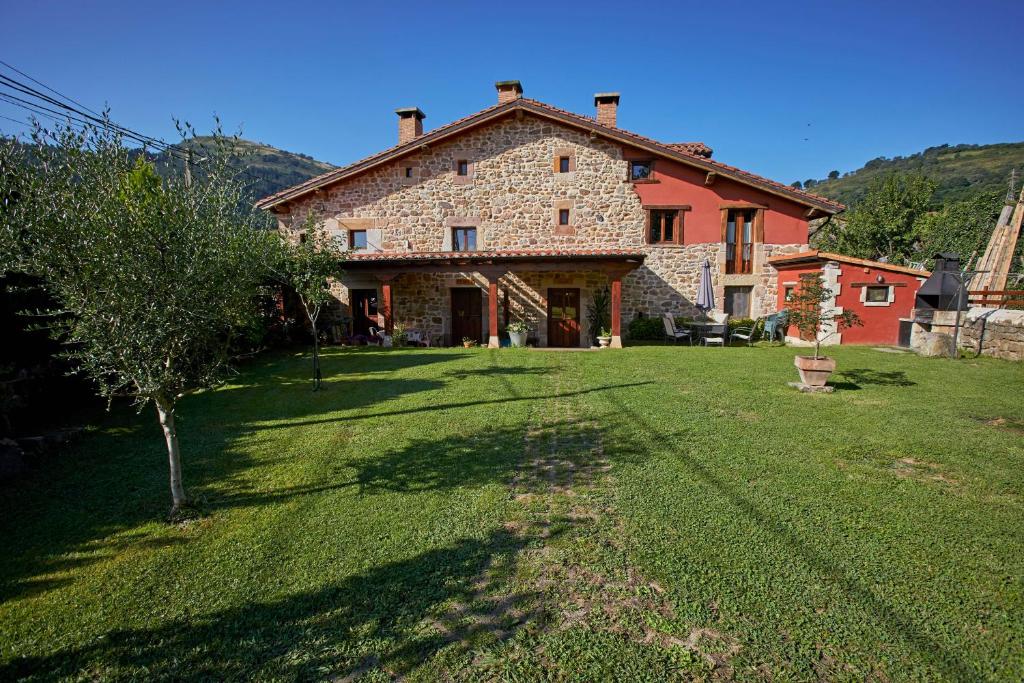 una gran casa de piedra con un patio verde en Sendero del Saja-Besaya, en Cobejo