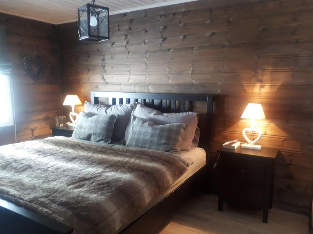 a bedroom with a bed with wooden walls and two lamps at Gautefall- High-standard cozy cabin with indoors whirlpool-tub and sauna in Treungen