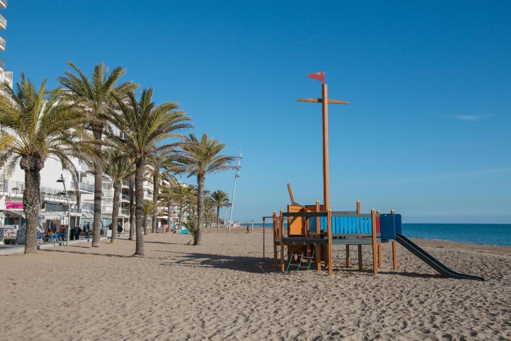 - une aire de jeux sur une plage avec des palmiers et l'océan dans l'établissement Casa Martina by MarCalma, à Calafell
