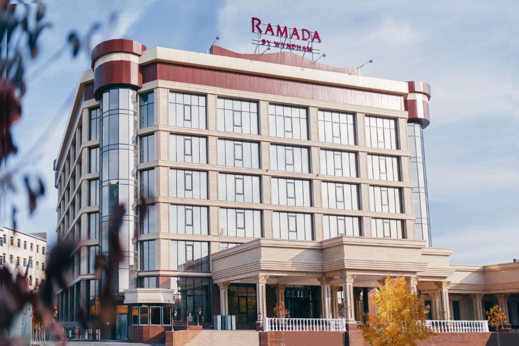 ein hohes Gebäude mit einem Schild darüber in der Unterkunft Ramada by Wyndham Shymkent in Schymkent