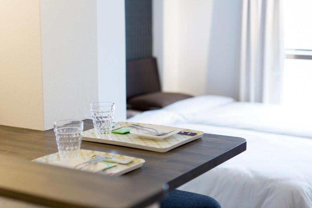 a coffee table with two plates and glasses on it at BEEHIVE APARTMENT Moriguchi in Osaka