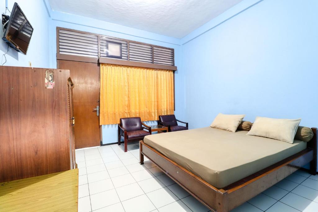 a bedroom with a bed and a tv and a chair at Hotel Bungurasih Syariah in Bungurasih