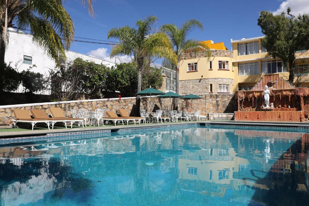 a swimming pool with chairs and a building in the background at Belisana in Ixtapan de la Sal