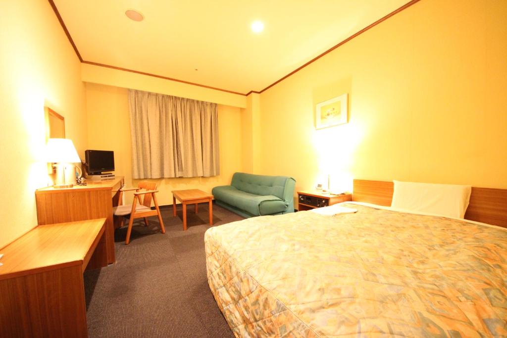 um quarto de hotel com uma cama, uma cadeira e uma secretária em New Gifu Hotel Plaza em Gifu