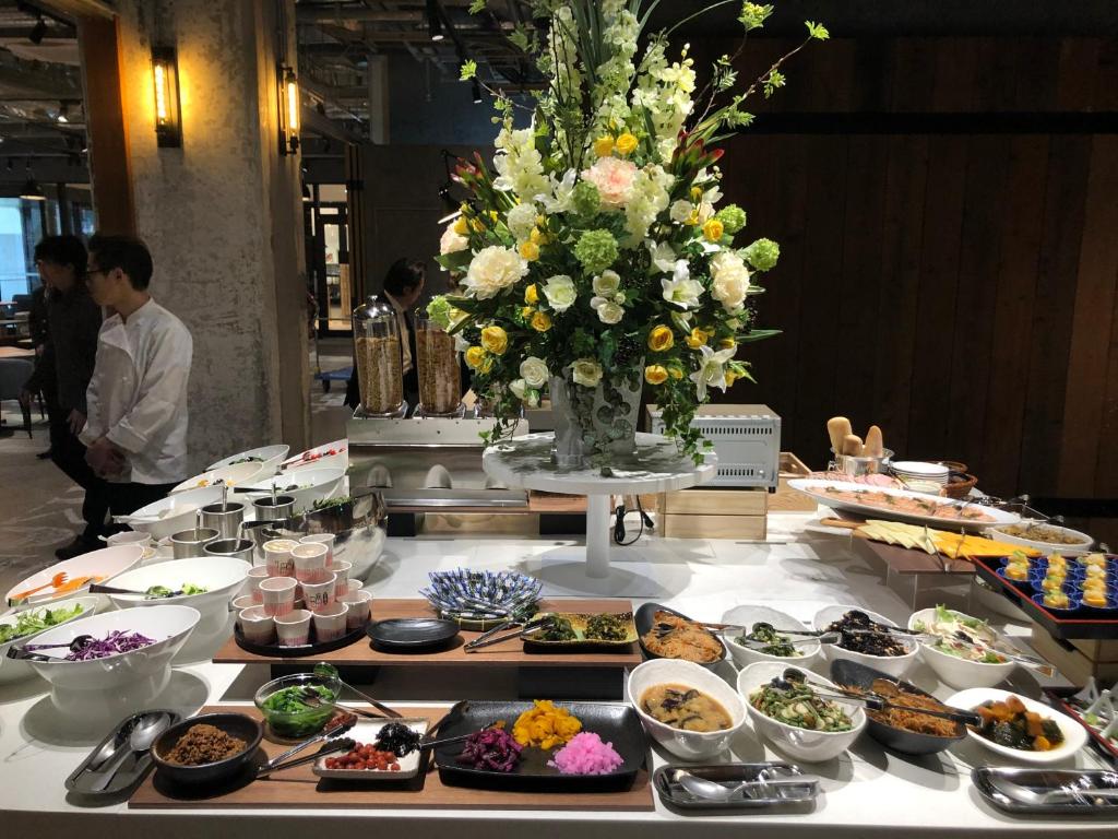 a table with plates of food and a flower arrangement at Citadines Namba Osaka in Osaka