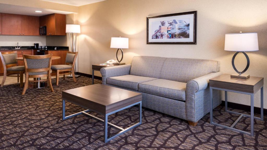 a living room with a couch and tables and a kitchen at Holiday Inn Hotel & Suites Warren by IHG in Warren